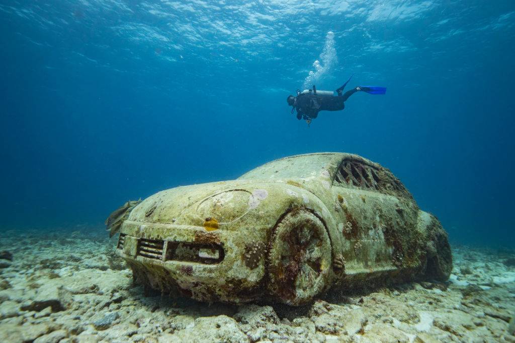 A diver kicks past a to scale-sized underwater statue of a volkswagon beetle off the coast of Isla Mujeres, Mexico