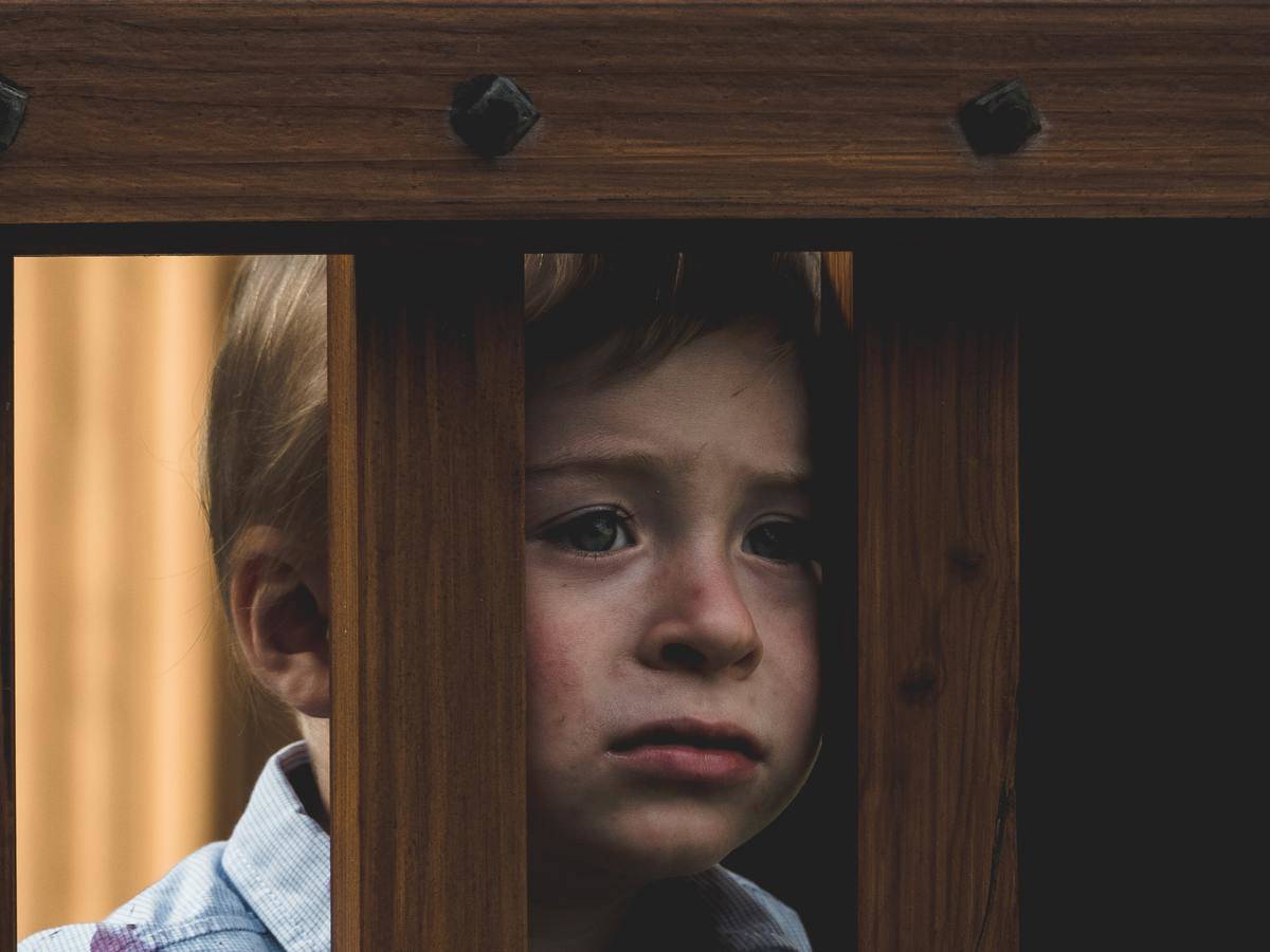 kid looks through rails looking sad