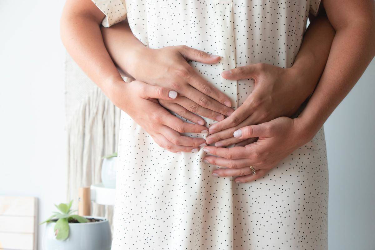 man holds pregnant woman from behind