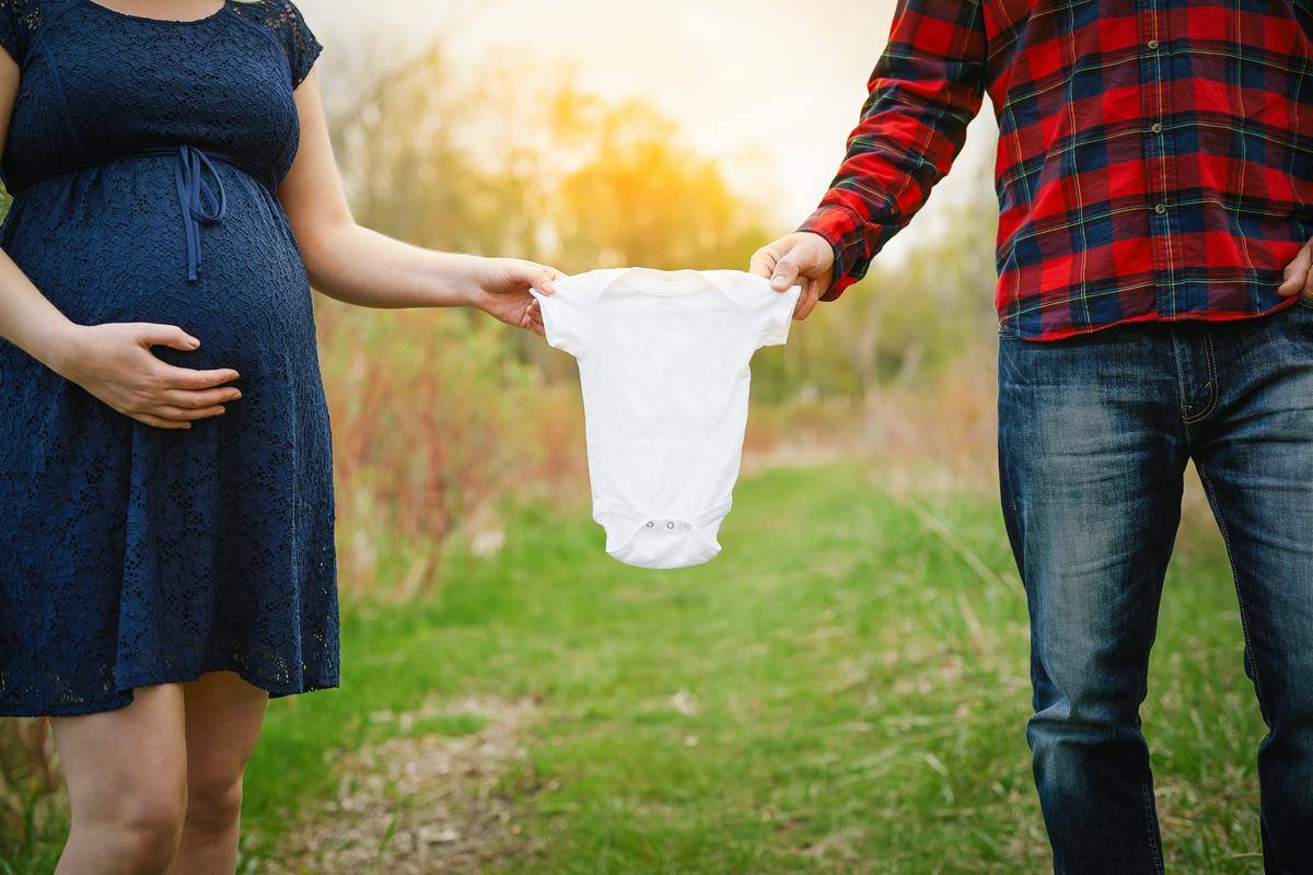 mom and dad hold baby's clothes from each end