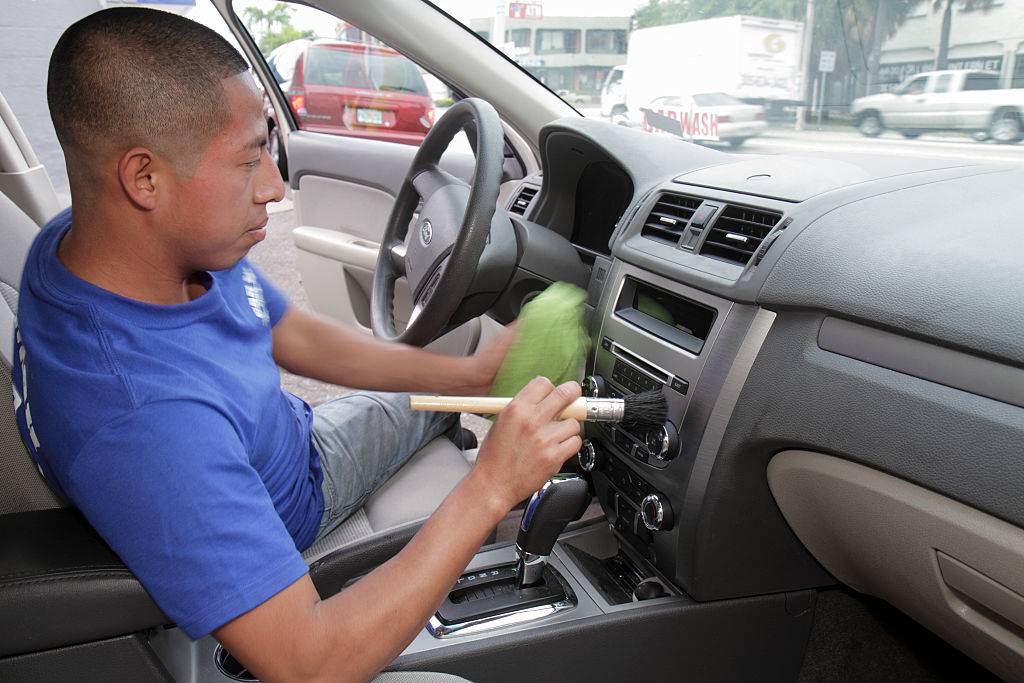 A man cleaning the dashboard of a car