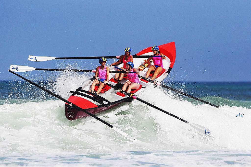 four women rowing a boat in piha, new zealand