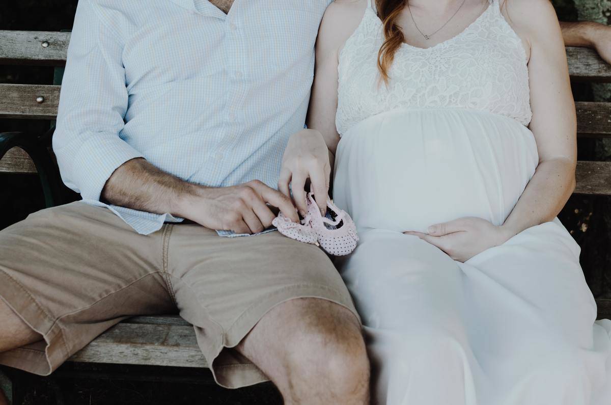 pregnant couple holding pink shoes