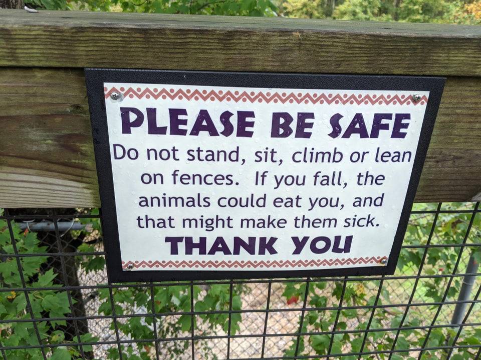 zoo sign: please be safe do not stand sit climb or lean on fences. If you fall, the animals could eat you, and that might make them sick