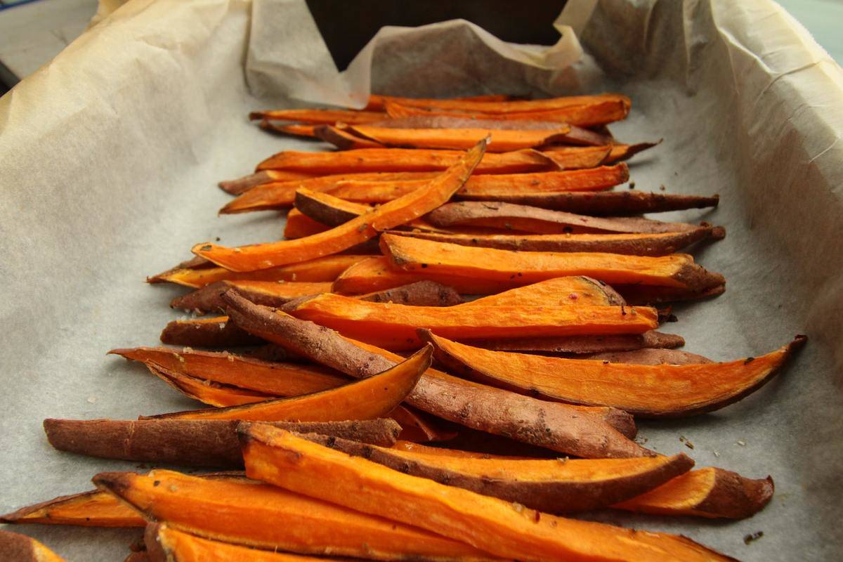 Sweet potato fries lie on a pan.