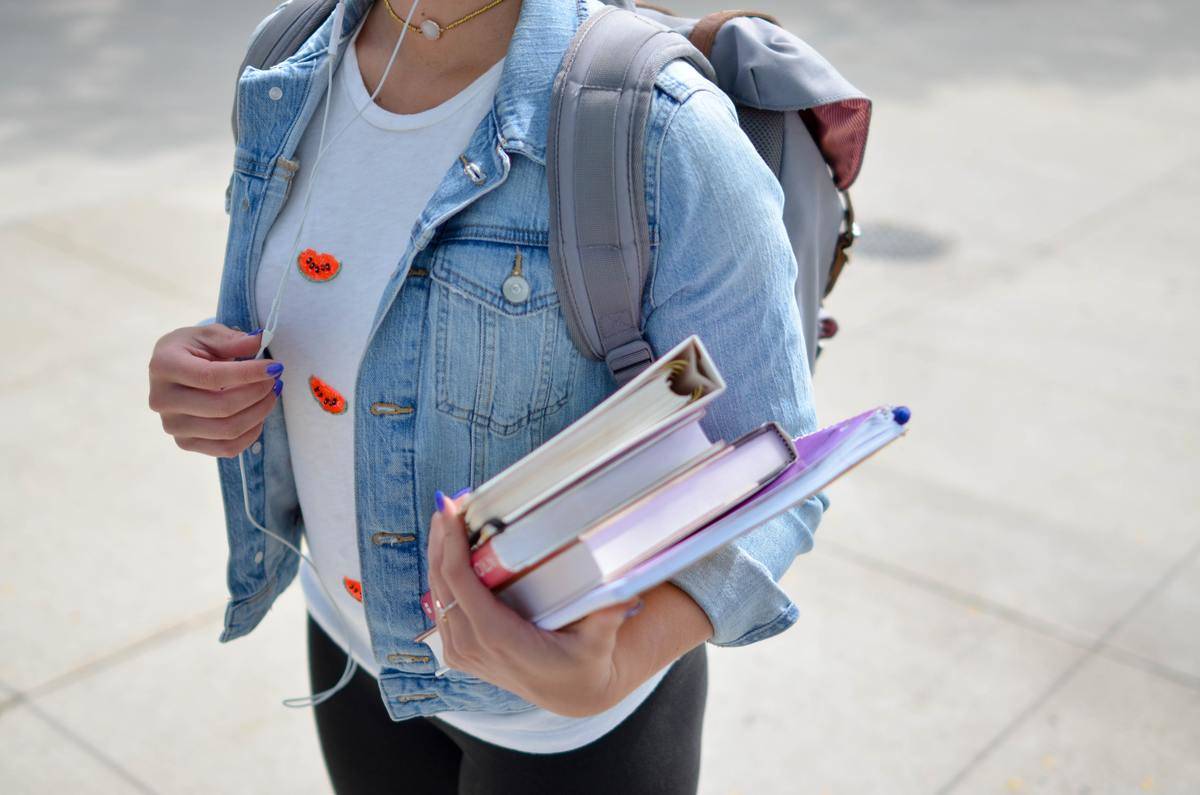 woman carrying textbooks in arms