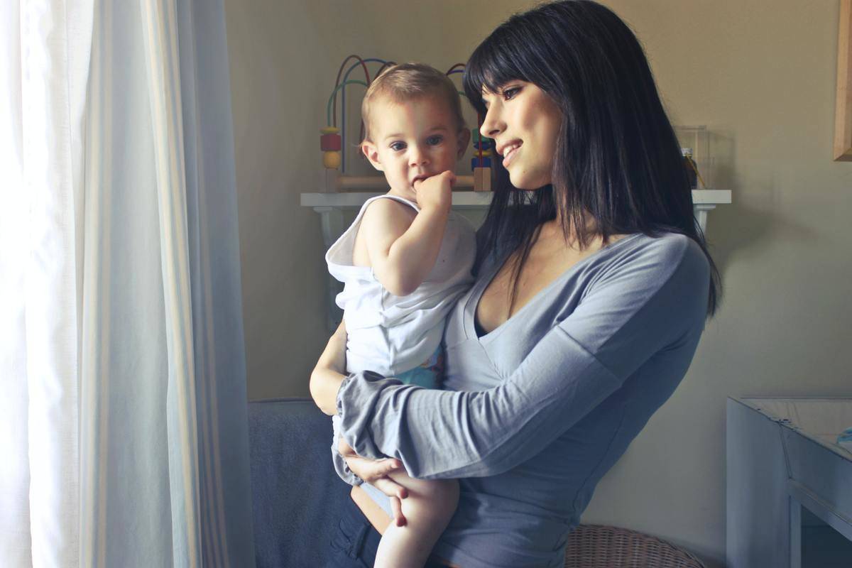 woman holding toddler looking out window