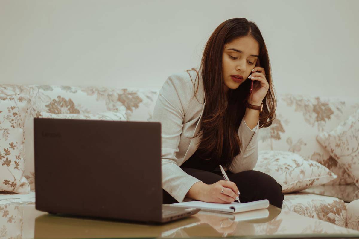 woman writing down notes and on thephone