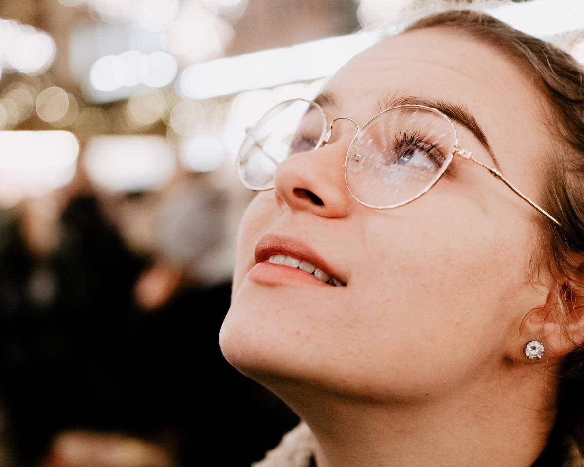 woman with glasses on looks up closeup