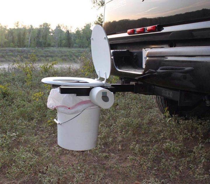 Bucket and toilet seat attached to back of pickup truck trailer hitch.