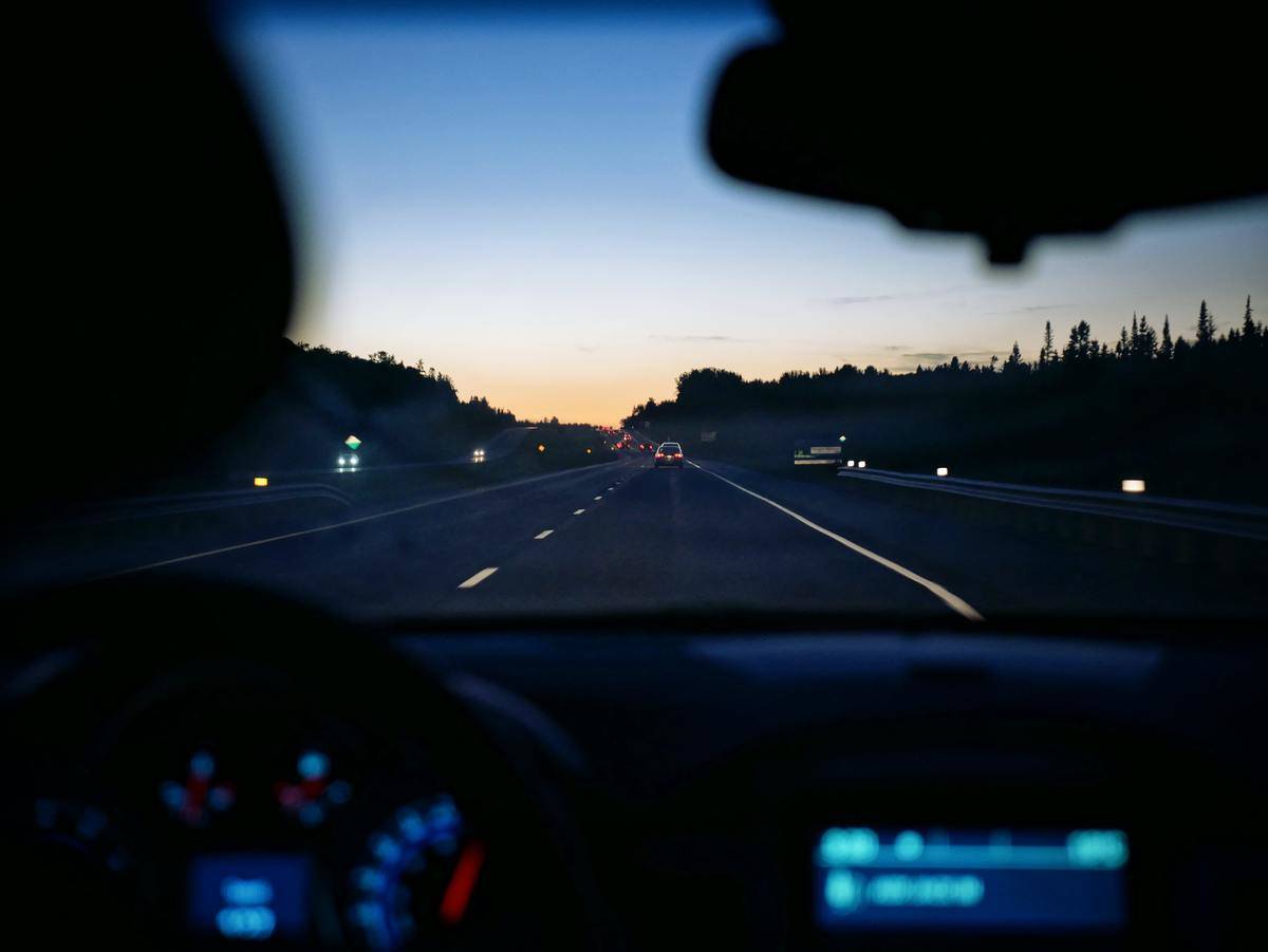 Dashboard and windshield view out of car at dusk