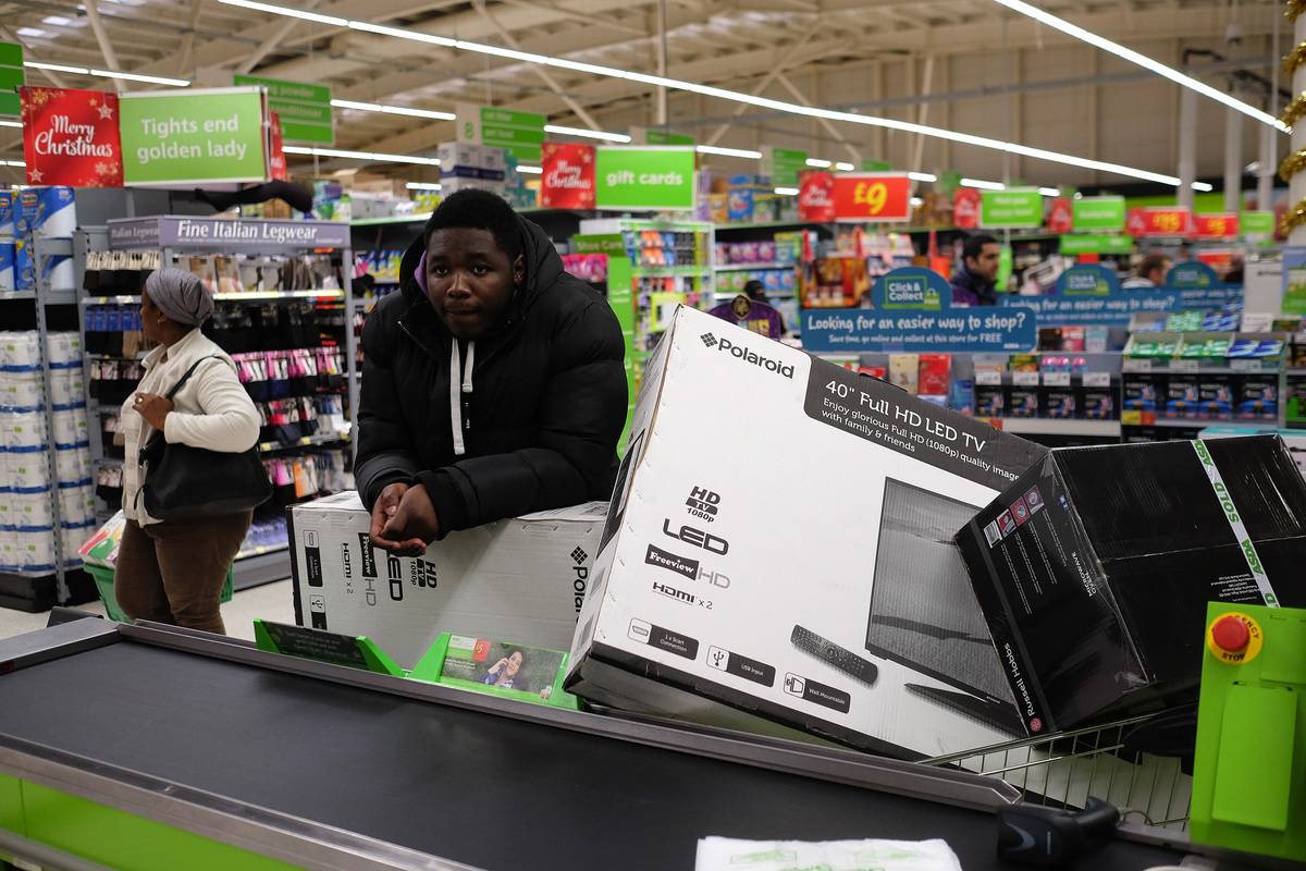 man standing at checkout with TV in cart