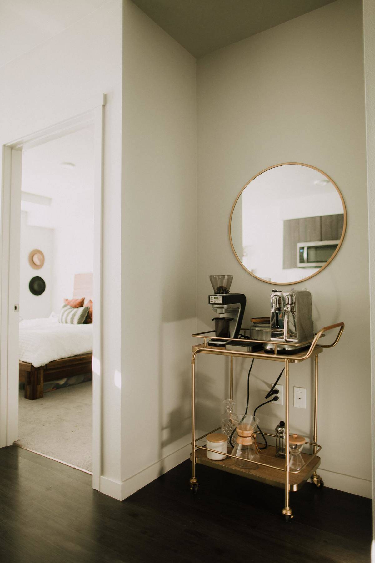 A bar cart holds kitchen utensils such as coffee makers.