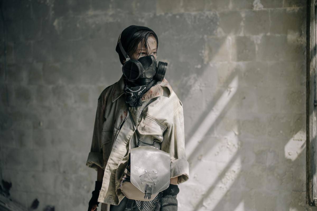 boy standing wearing gas mask and old clothes