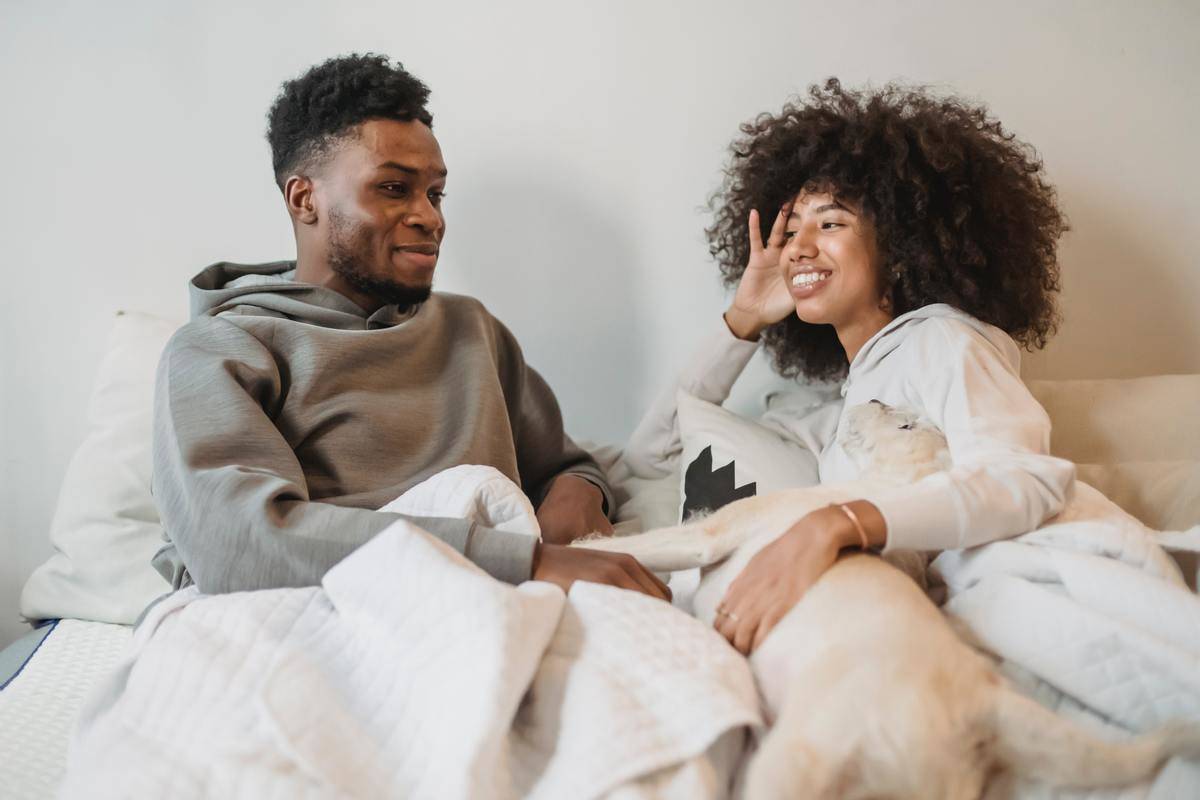 man and woman in bed smiling talking
