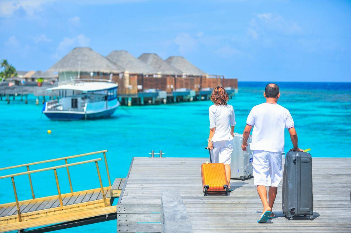 couples in Maldives carrying suitcase