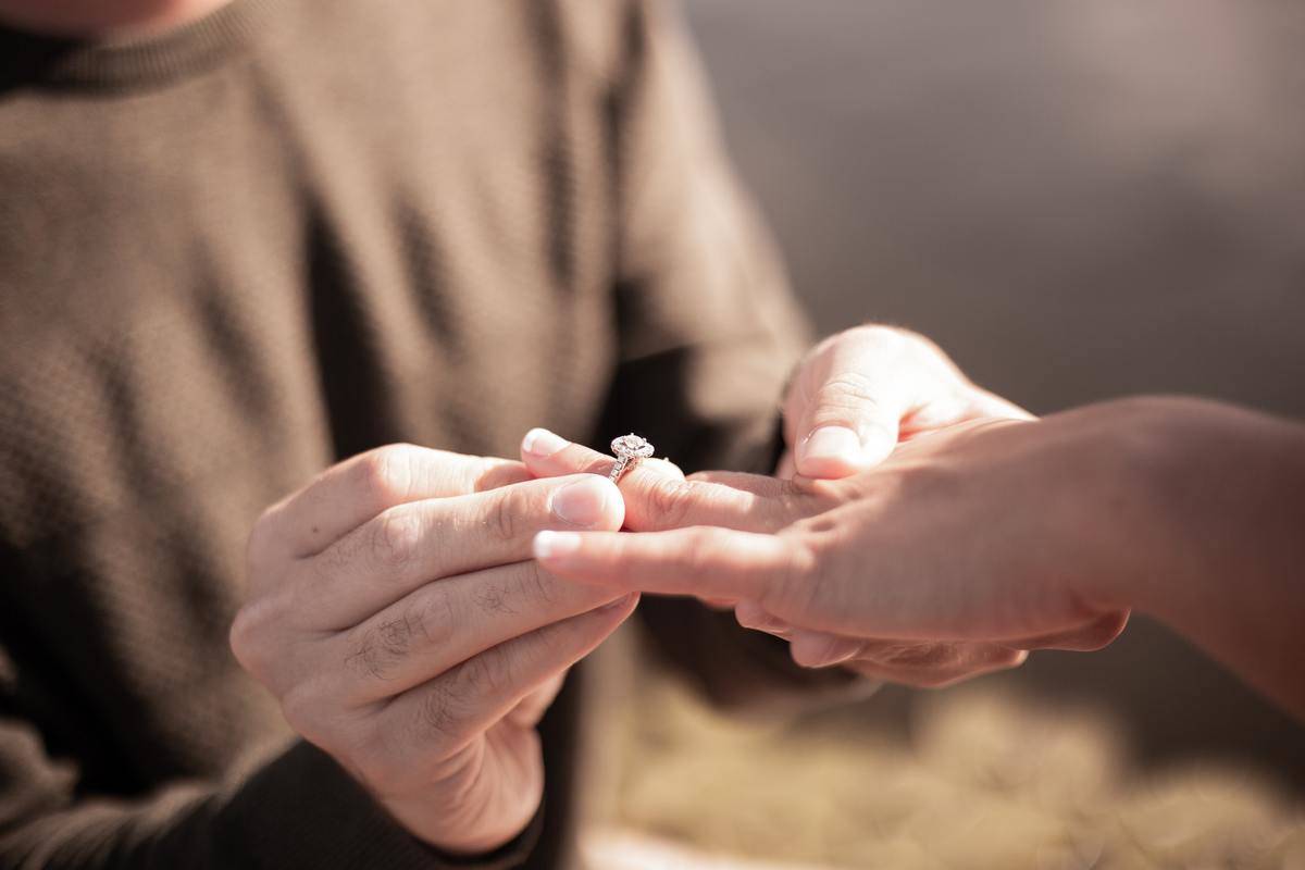 man putting engagement ring on woman's hand