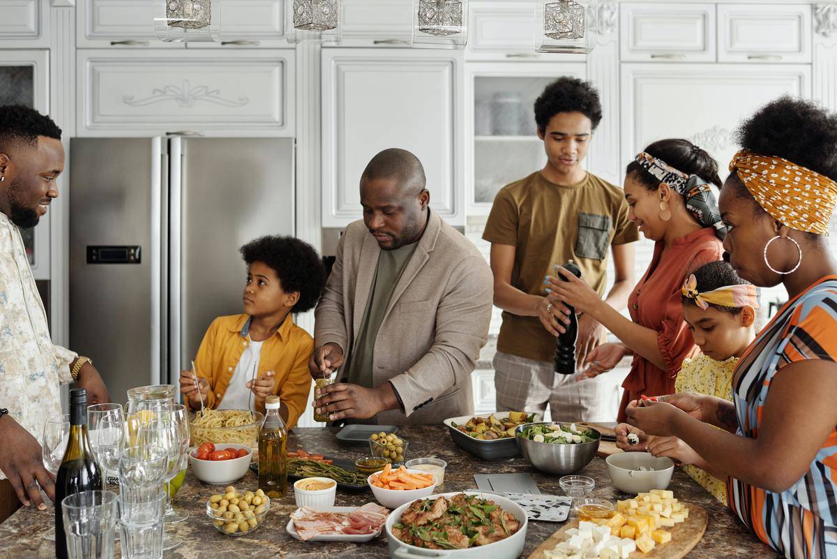 family at home standing around kitchen island covered in food