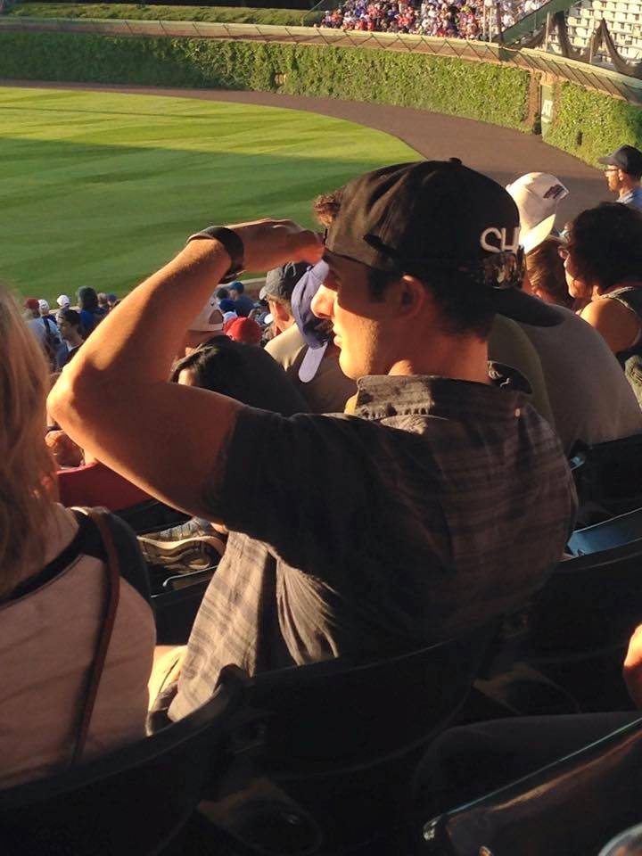 ignoring his hat but using his hand to block the sun