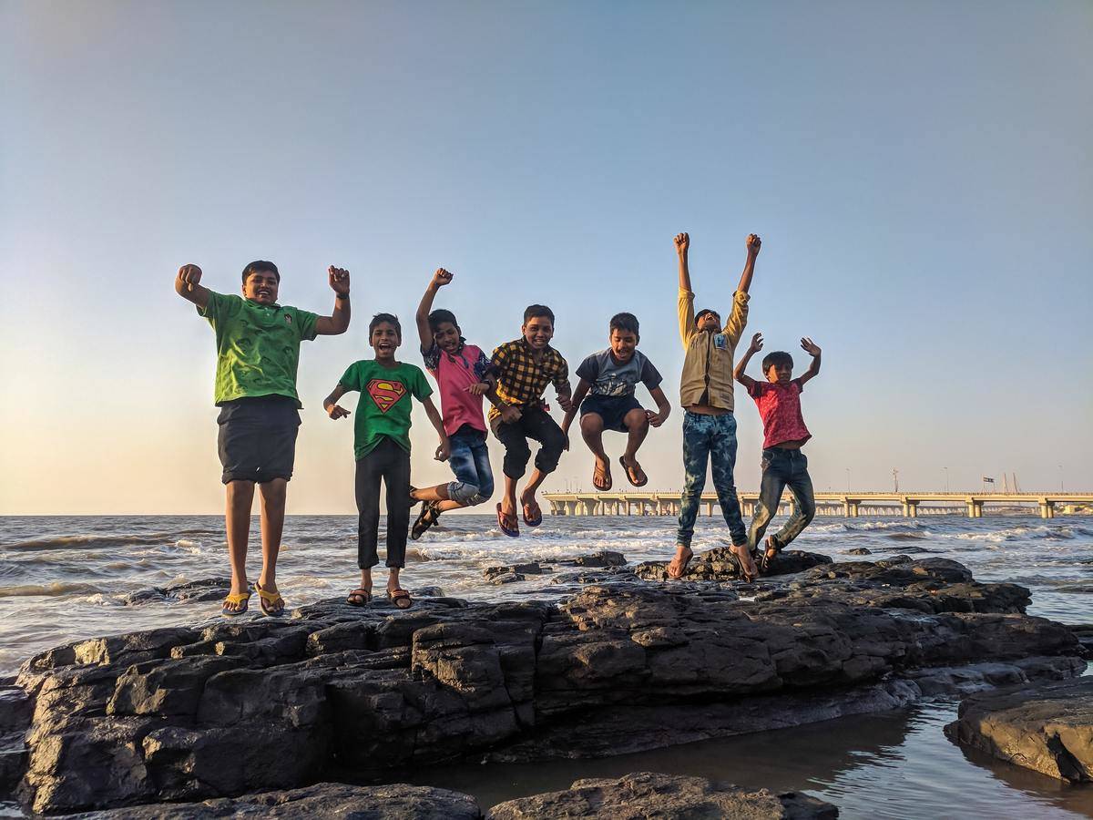 kids jumping by the water on rocks