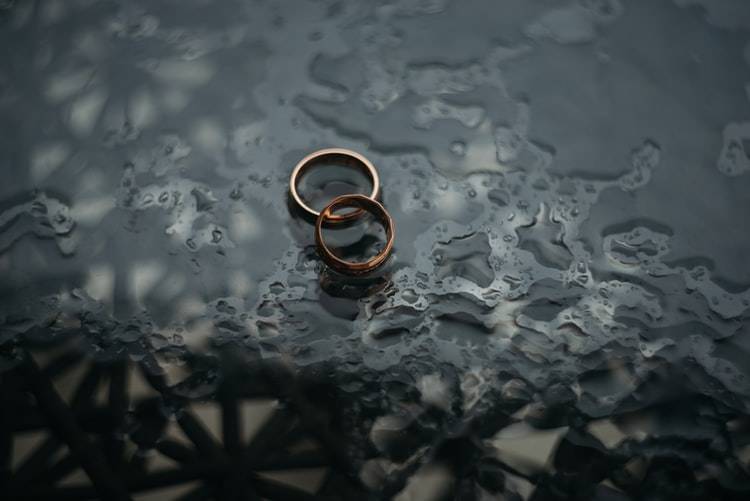 two wedding rings photographed on a rain covered table