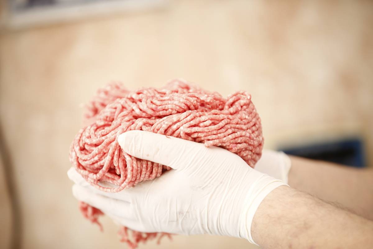 A butcher holds a handful of ground meat