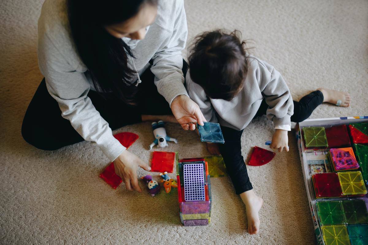 woman on floor playing with toddler