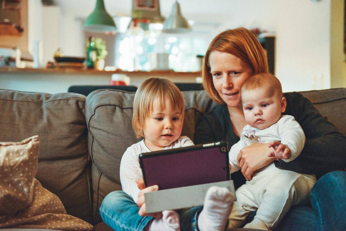 mom and two kids looking at an iPad