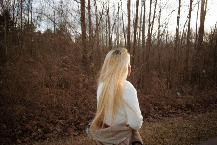 Back shot of blonde girl walking in the forest
