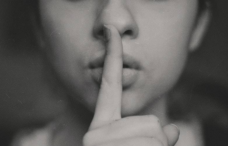 woman putting a finger against her lips to shush somebody