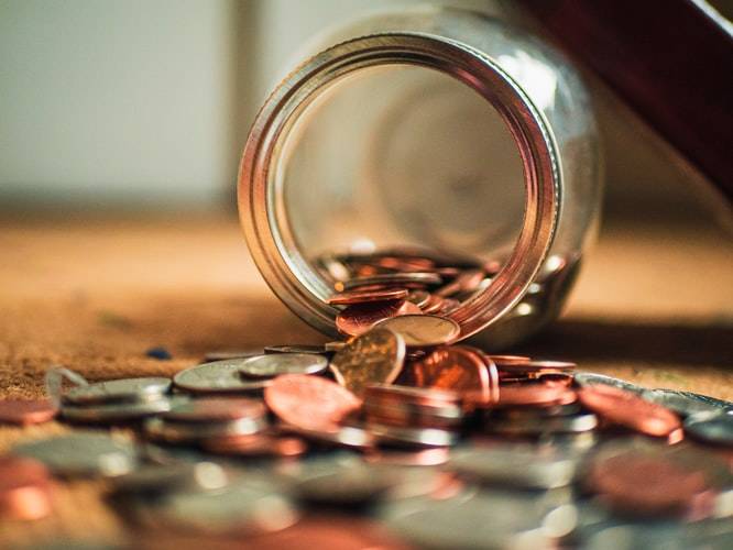 Coins spilling out of a glass jar