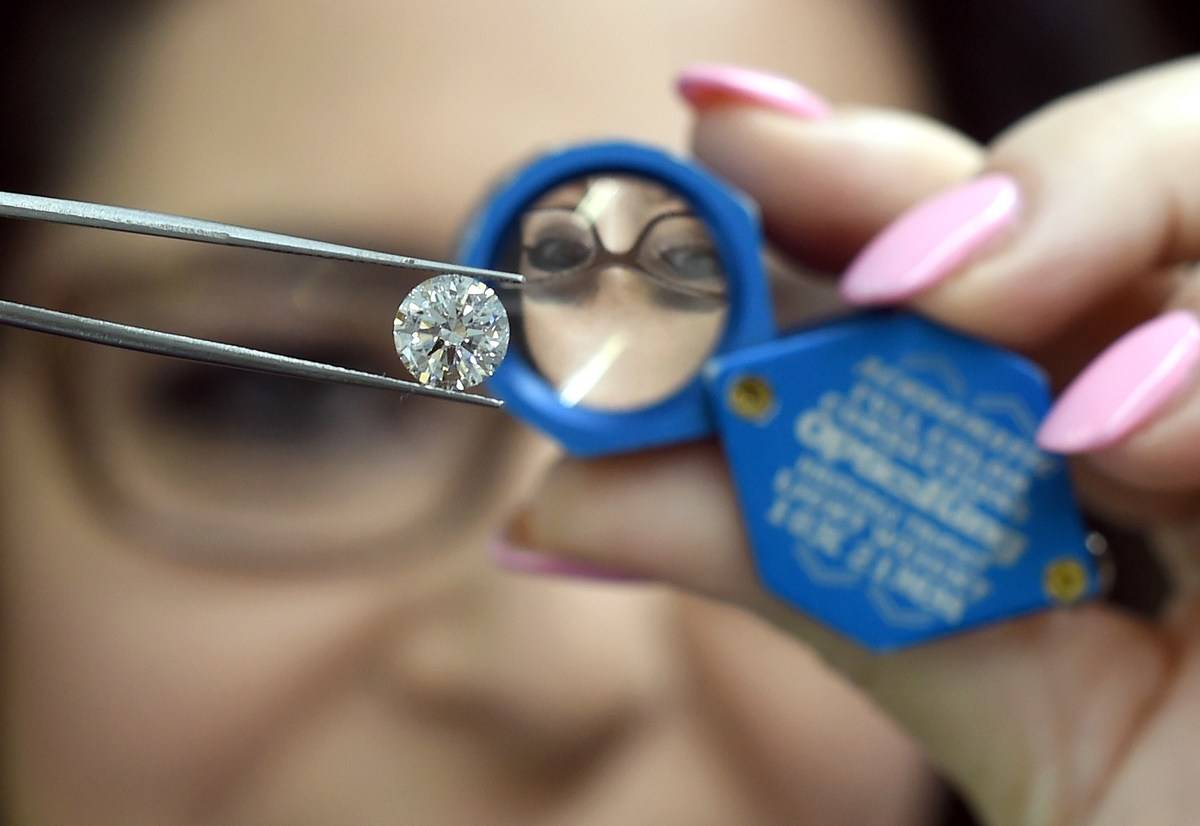 Woman holds lab grown diamond in front of a magnifying glass