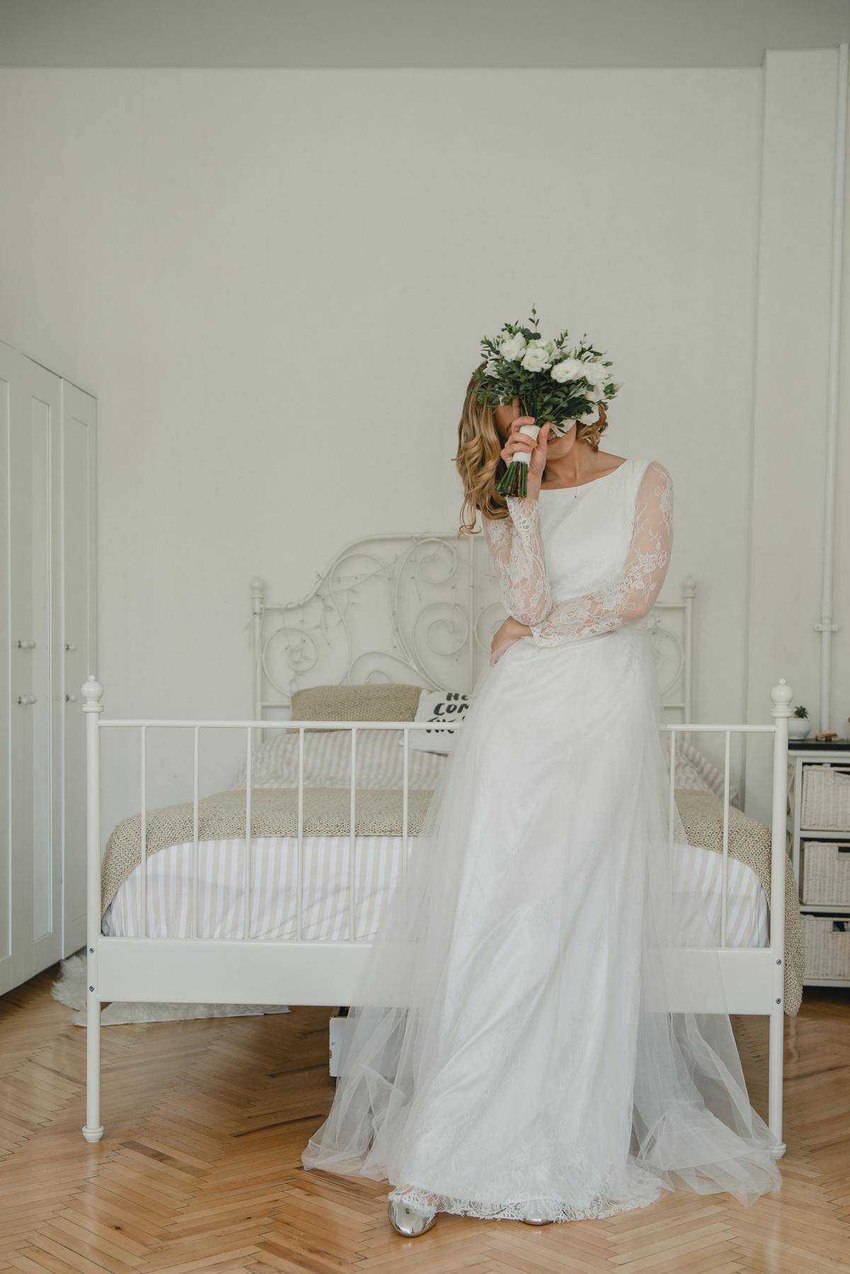 woman in wedding dress in bedroom holding bouquet