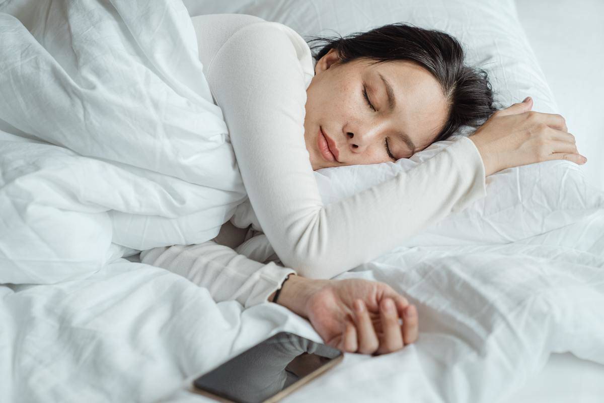woman sleeping in bed with her phone 
