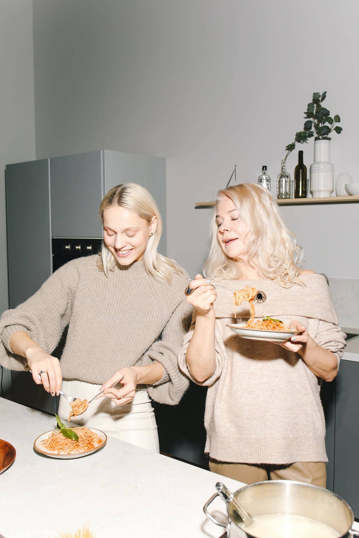 a young and an older woman eating spaghetti