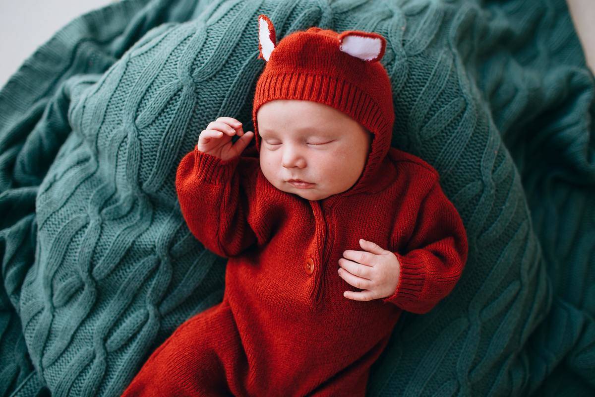 Tiny baby sleeping on knitted blanket