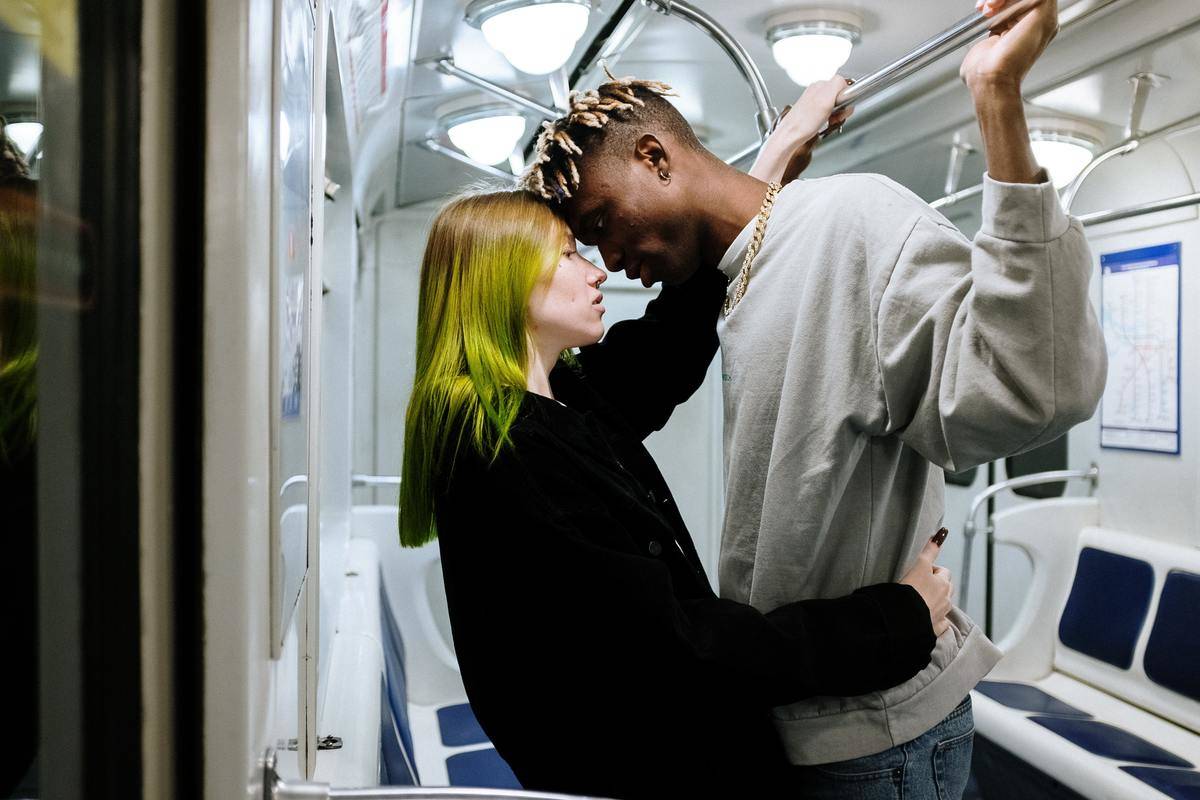 Couple hang on to each other and stability bars on subway transit