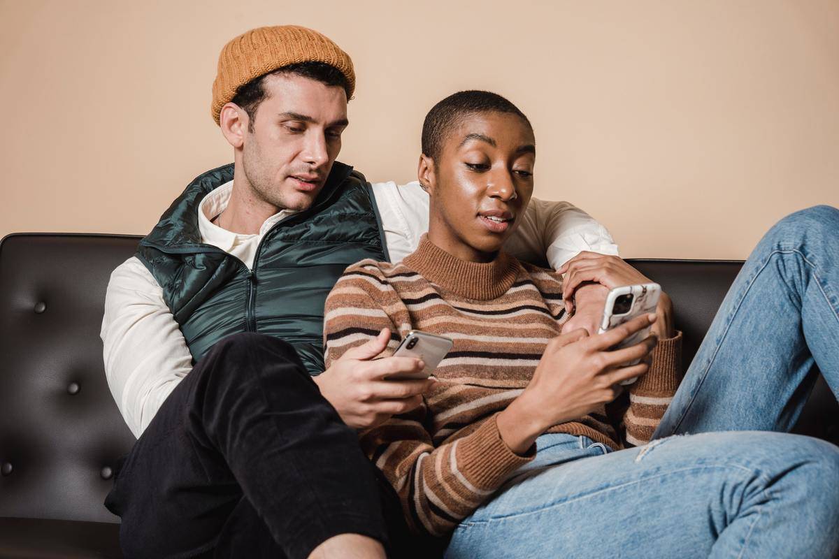 Couple on couch both on smartphones