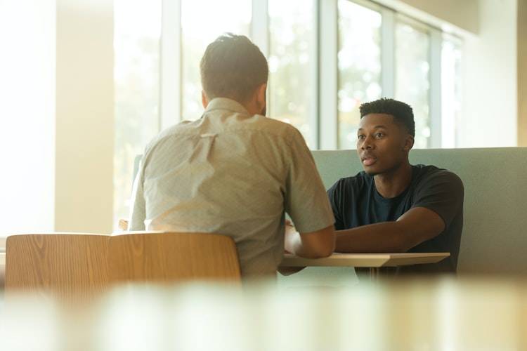 two men talking to one another at a table