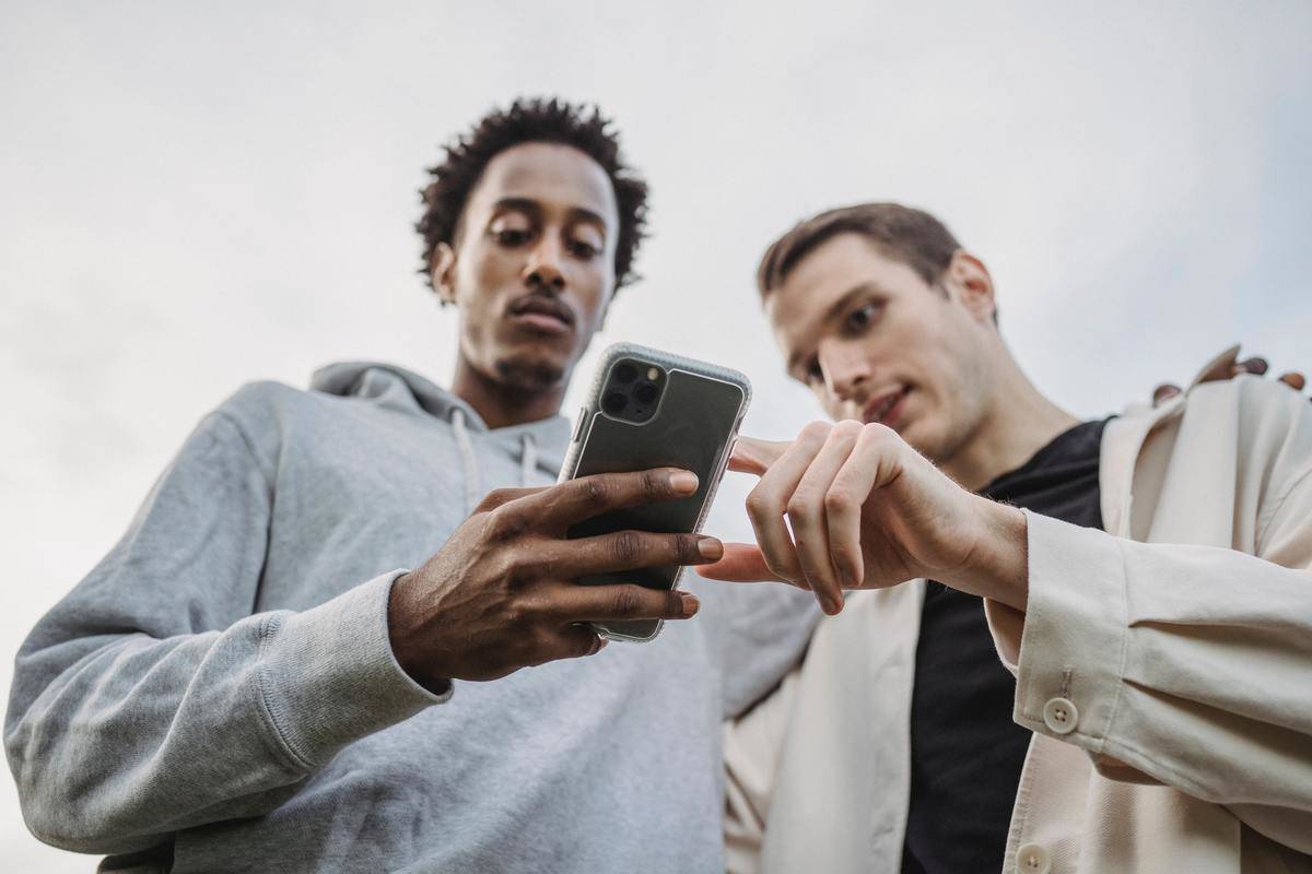 Man shows picture on his smartphone to his friend who is holding the phone