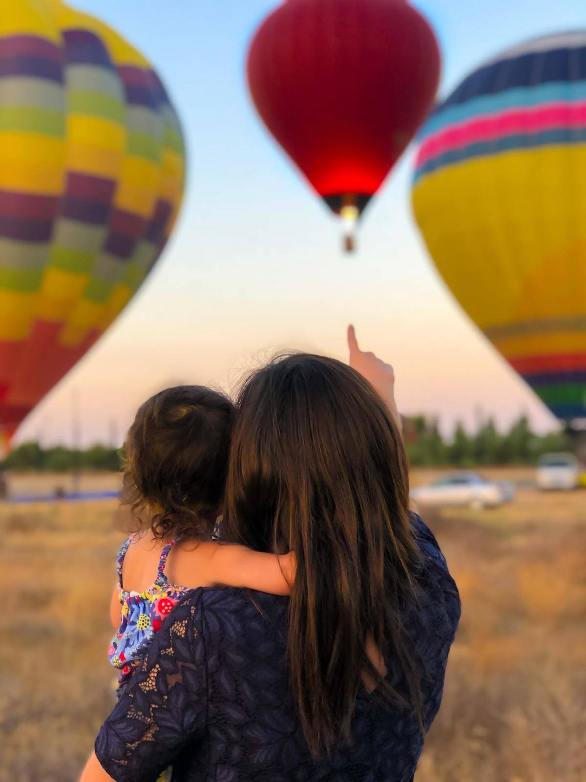 Mother and daughter watch hot-air balloons take off