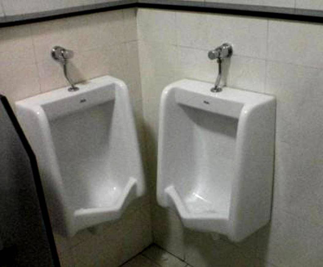 urinals on two walls of corner, only an inch apart