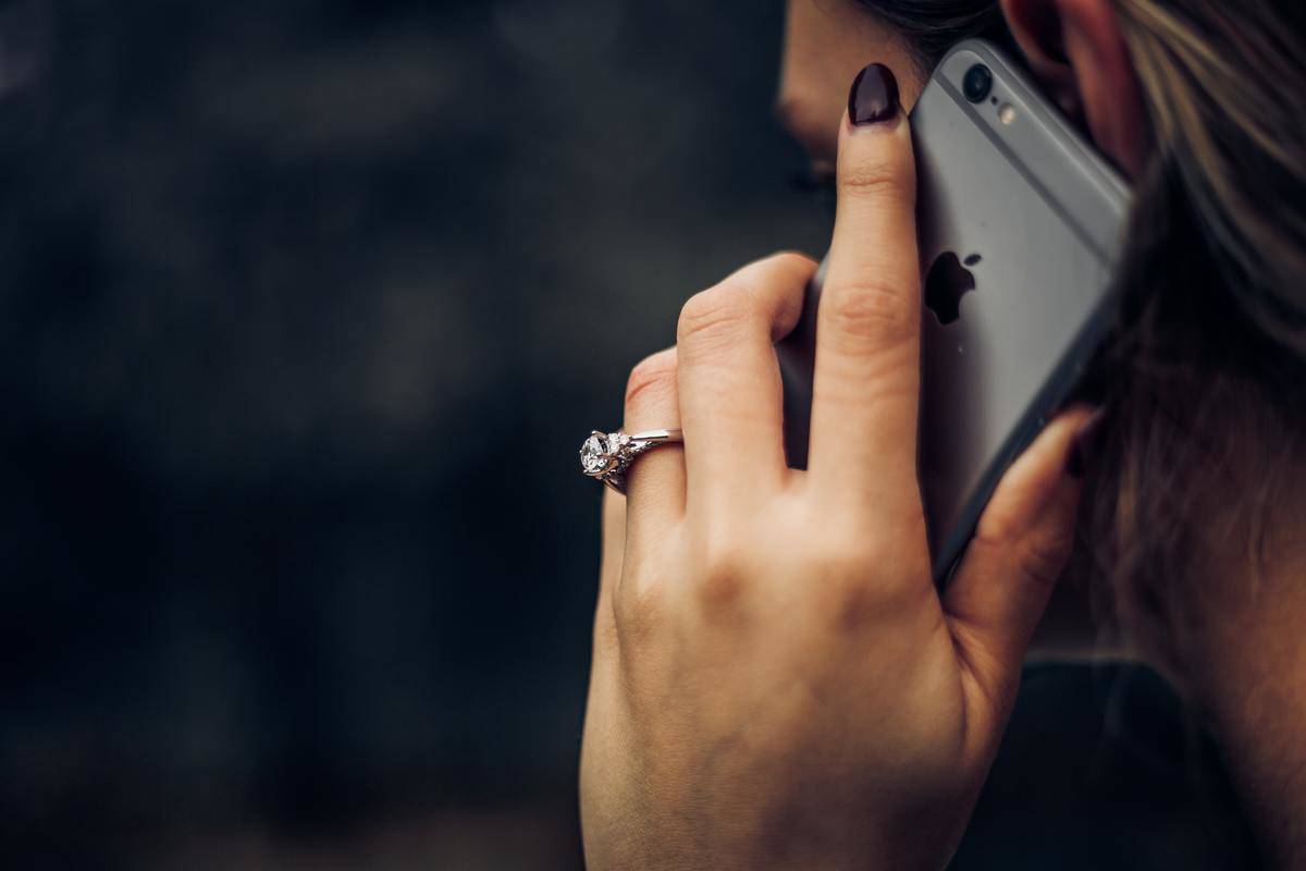 Woman wearing engagement ring talks on iPhone