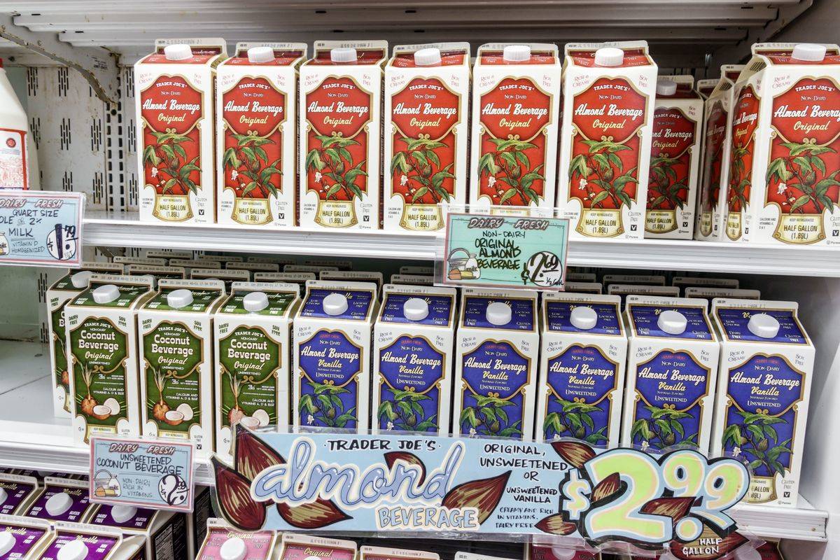 Cartons of almond milk line supermarket shelves.