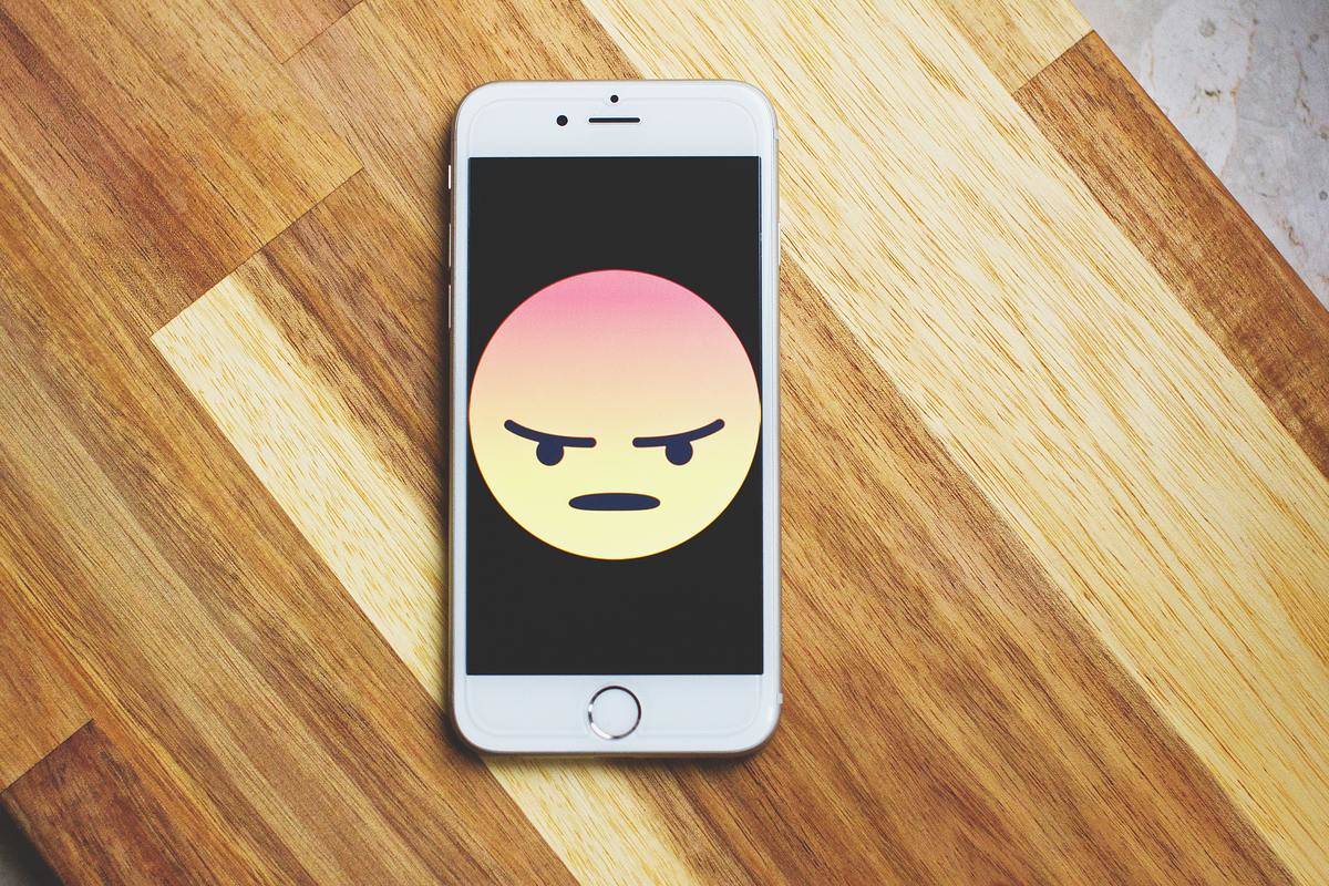 angry emoji in center of white iPhone