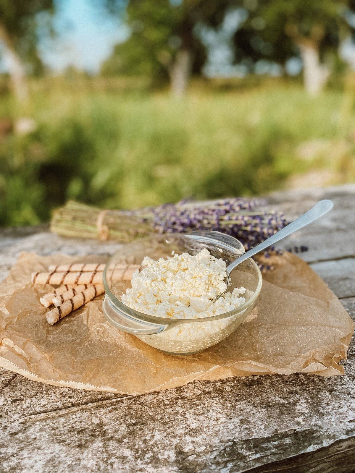A bowl of cottage cheese sits outside on a wooden table.