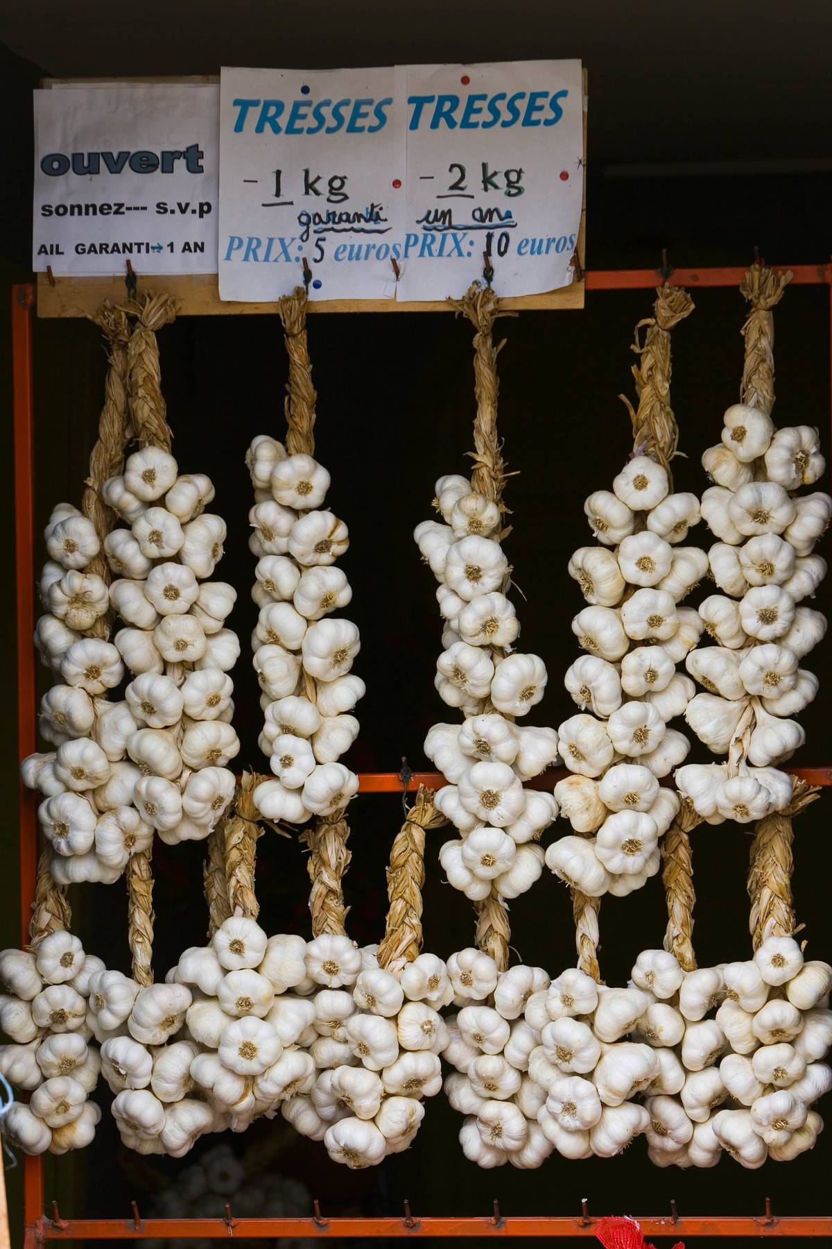 Strings of garlic bulbs are for sale.