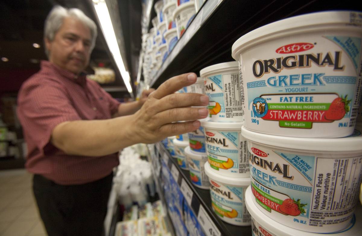 A customer reaches for a tub of Greek yogurt in a supermarket.