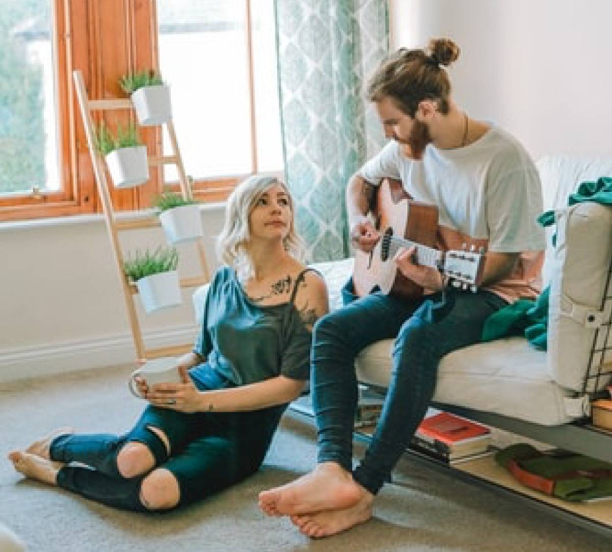 woman staring up at man lustfully while he plays the guitar
