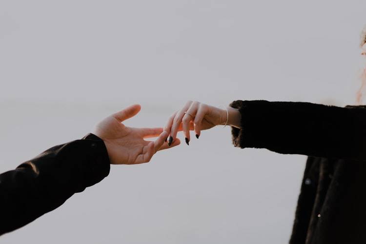 two people barely holding hands shot against a white background